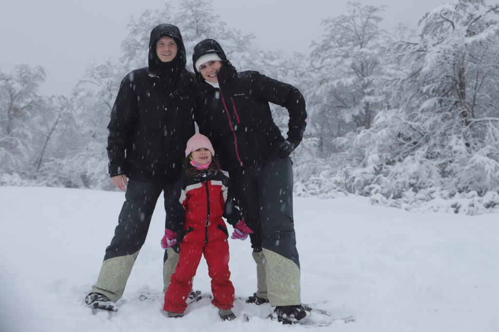 Familia de mãe, pai e filha na neve