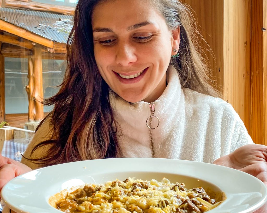 Mulher olhando prato com massa em restaurante