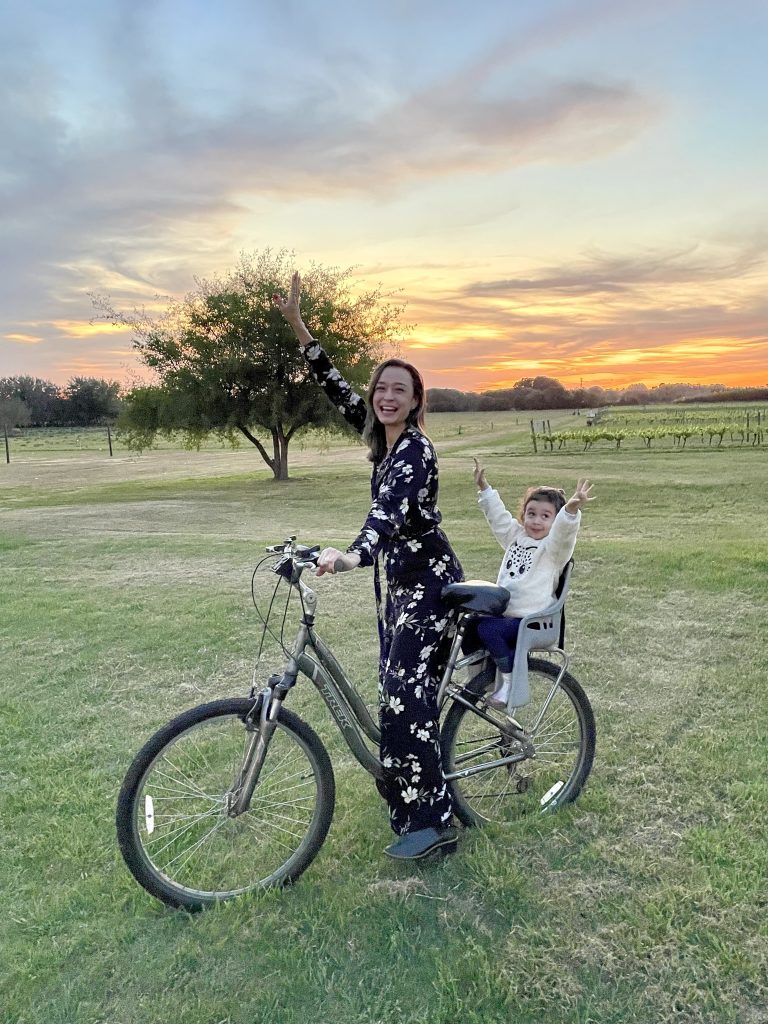 Mãe com filha em bicicleta no pôr do sol