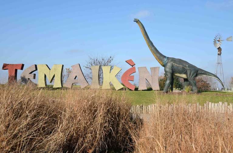 letreiro com escultura de dinossauro ao lado