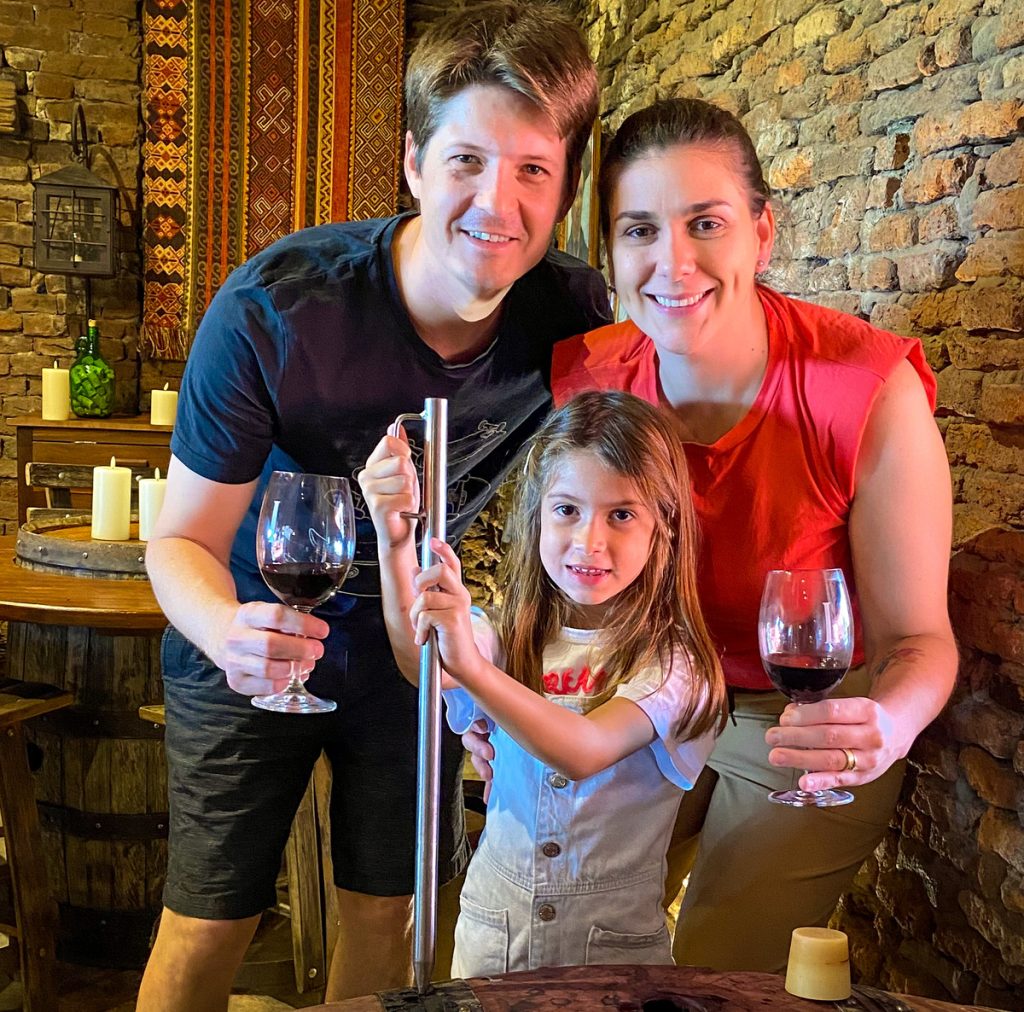 pai, mãe e menina com taças na mão em foto de família