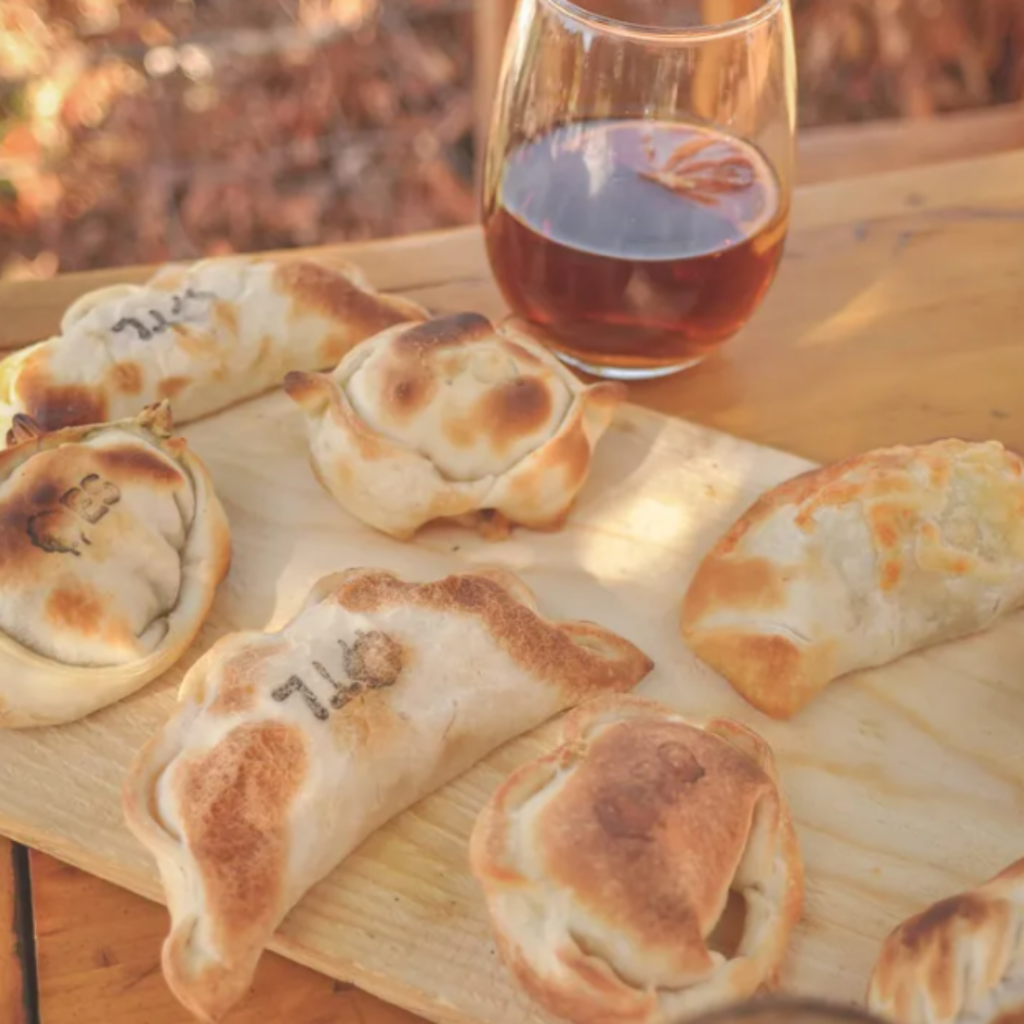 tábua com empanadas e copo de cerveja