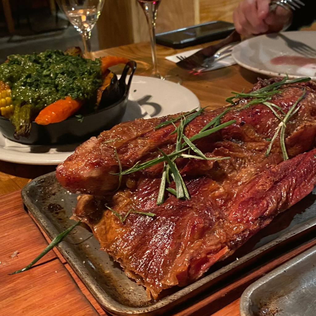 mesa com grande prato de carne com ervas