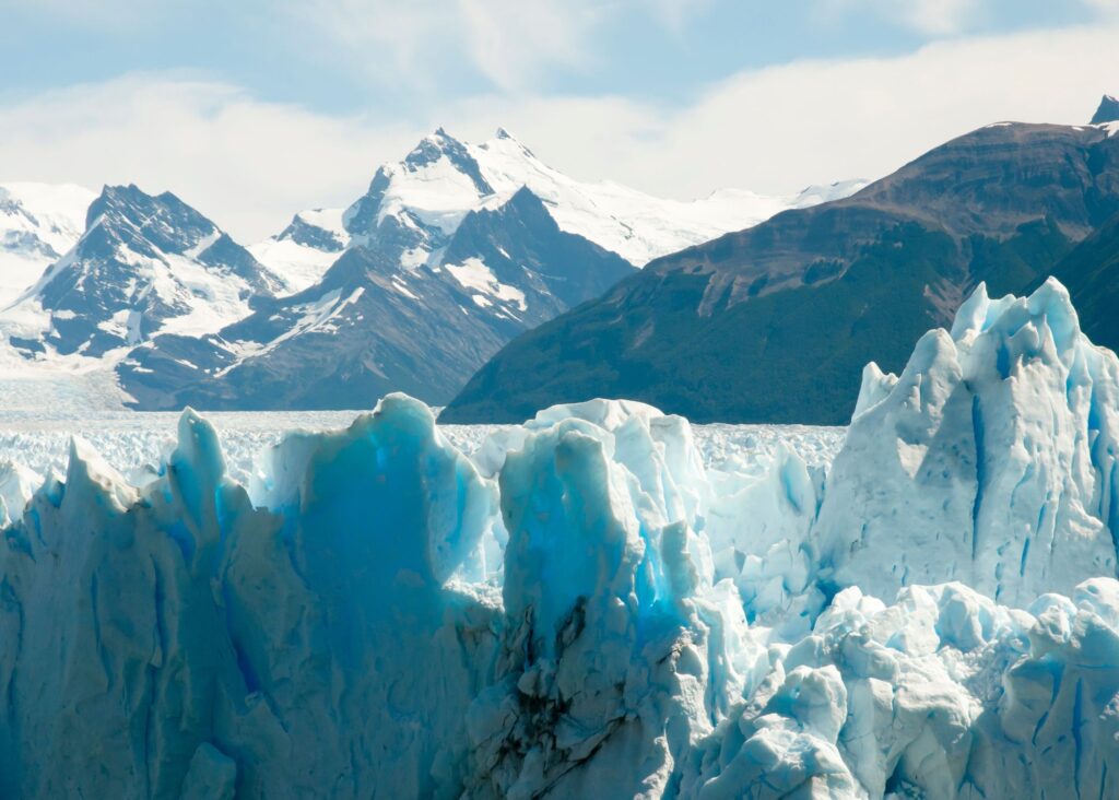uma parte de glaciar com montanhas ao fundo