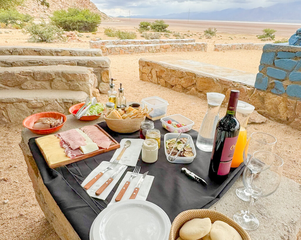 mesa com vinhos e frios com vista de área desértica
