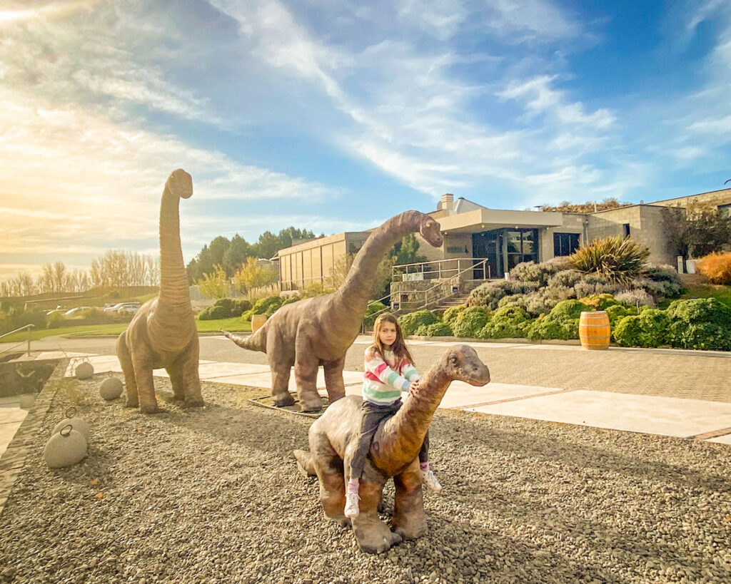 menina em cima de esculturas de dinossauro