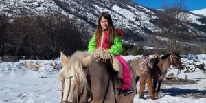 menina montada em cavalo em montanha de neve