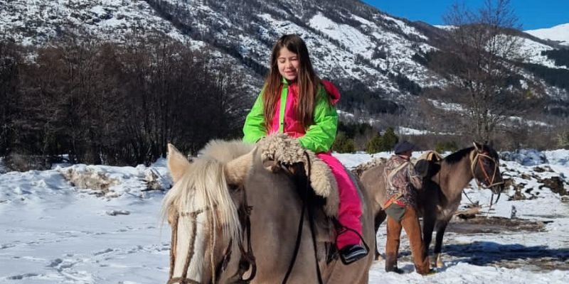 menina montada em cavalo em montanha de neve