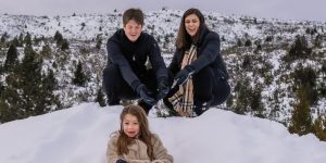 pai, mãe e filha brincando na neve