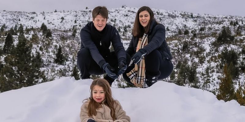 pai, mãe e filha brincando na neve