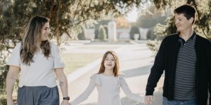 mãe, filha e pai e de mãos dadas andando em parque