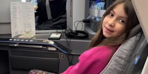 menina sentada em poltrona de avião