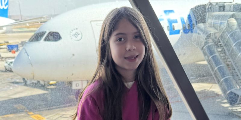 menina dentro de aeroporto com avião ao fundo
