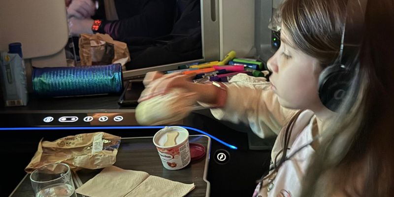 menina sentada comendo dentro de avião