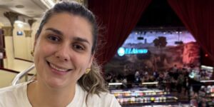 mulher sorrindo com livraria ao fundo