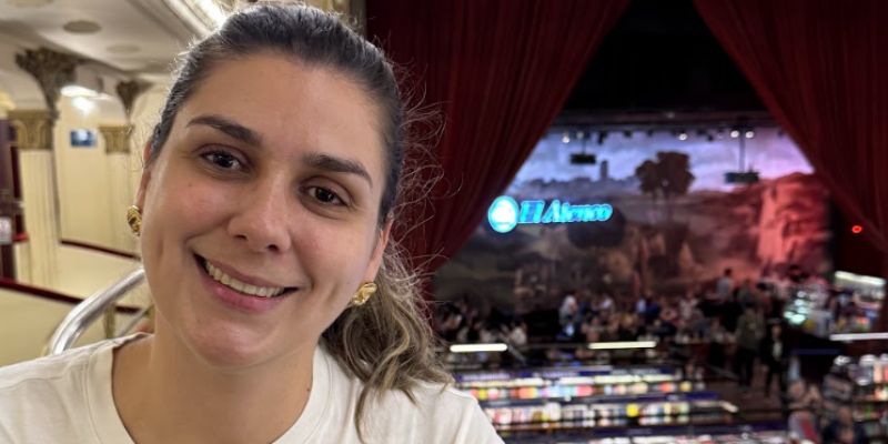 mulher sorrindo com livraria ao fundo