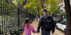 pai e menina de costas andando de mãos dadas